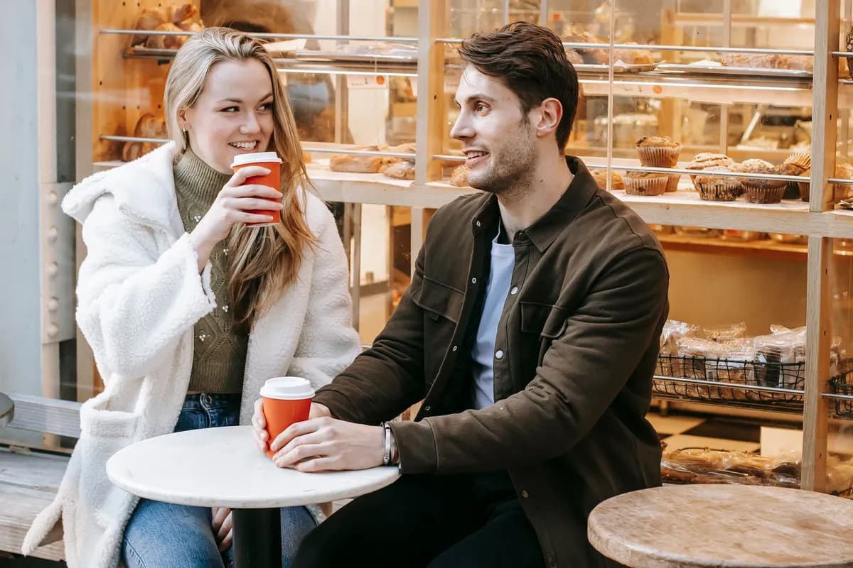 A couple talking over coffee at a small table outside a bakery